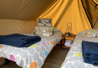Inde i et teepee-telt, Nomad Bivouac, med to senge og picnic-kurv på Camping Seasonova Le Point du Jour, Frankrig.