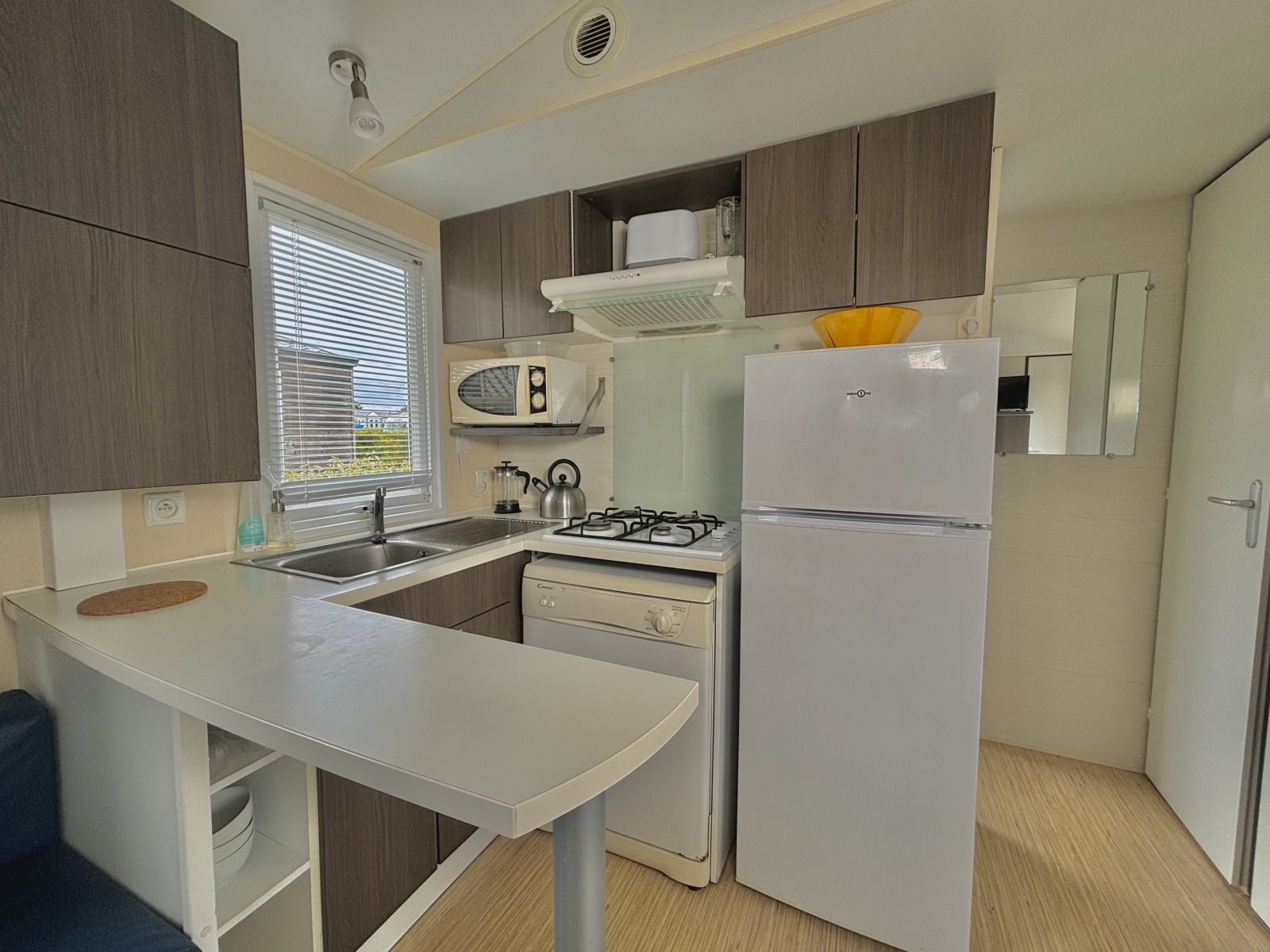 Moderne kleine keuken in glamping accommodatie met fornuis, koelkast, magnetron en kastruimte.