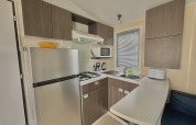 Cocina glamping moderna con nevera, estufa de gas, microondas, fregadero y gabinetes de madera.