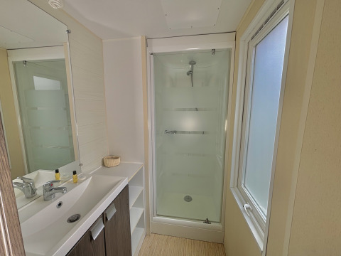 Moderne badkamer met douche, wastafel en groot raam in een glampingverblijf met daglicht.