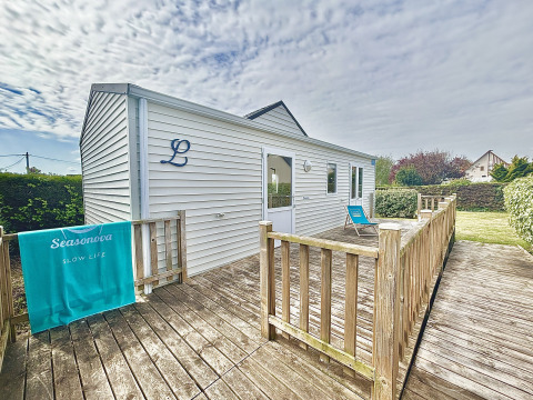 Cabaña accesible 'Cottage PMR' para discapacitados, terraza de madera y silla de playa en un jardín.