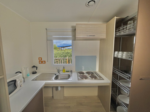 Cocina accesible en cabaña adaptada para discapacitados con estufa, fregadero y estantes en Francia.