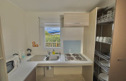 Cocina accesible en cabaña adaptada para discapacitados con estufa, fregadero y estantes en Francia.