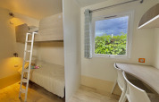 Bright room with bunk beds, desk, and window at Cottage PMR, Camping Seasonova Le Point du Jour, France.