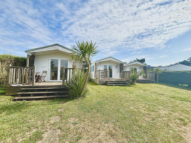 Outdoor view of Cottage Zen cabins at Camping Seasonova Le Point du Jour in France under a clear blue sky.