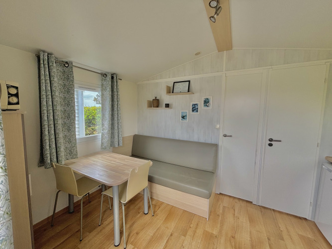 Helles, gemütliches Wohnzimmer im Cottage Zen auf Camping Seasonova Le Point du Jour, Frankreich, mit Esstisch.