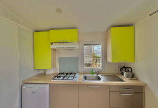 Cocina moderna en Cottage Zen en Camping Seasonova Le Point du Jour, Francia, con armarios verdes brillantes.