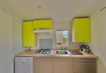 Cocina moderna en Cottage Zen en Camping Seasonova Le Point du Jour, Francia, con armarios verdes brillantes.