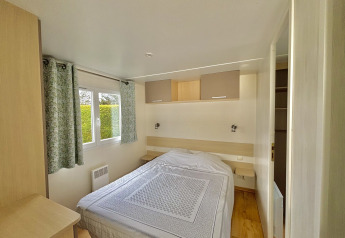 Dormitorio en el Cottage Zen de Camping Seasonova Le Point du Jour en Francia con cama doble y ventana.