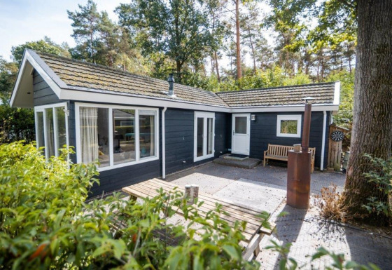 Exterior del Nature Chalet en un entorno boscoso, con terraza, banco de madera y detalles modernos.