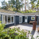 Udendørsbillede af Nature Chalet, omgivet af skov, med terrasse, bænk og moderne udsmykning.