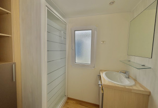 Baño con ducha, lavabo, espejo y ventana en Cottage Zen en Camping Seasonova Le Point du Jour en Francia.