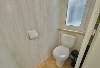 Lyst og lille badeværelse med toilet, toiletpapirholder og vindue i Cottage Zen, Camping Seasonova Le Point du Jour.