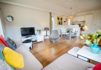 Lyst og moderne opholdsrum i Nature Chalet på Bospark Markelo, Holland, med åbent køkken og farverige detaljer.