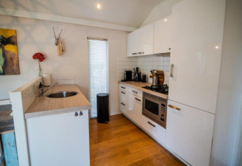 Modern kitchen in Nature Chalet at Bospark Markelo, Netherlands, with white cabinets, wood floor, and decor.