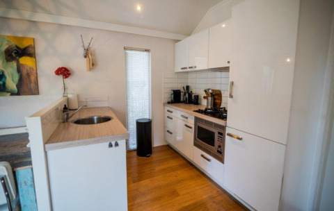 Modern kitchen in Nature Chalet at Bospark Markelo, Netherlands, with white cabinets, wood floor, and decor.