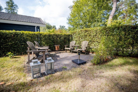 Coin salon extérieur avec chaises en bois au Nature Chalet, Bospark Markelo, Pays-Bas.