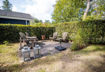 Udendørs siddeområde med træstole og lanterner ved Nature Chalet, Bospark Markelo, Holland.