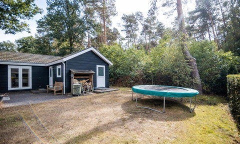 Vista del Nature Chalet en Bospark Markelo, Países Bajos, con una cama elástica y zona boscosa.