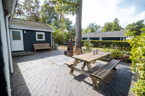 Espace extérieur du Nature Chalet au Bospark Markelo, Pays-Bas, avec banc en bois et table de pique-nique.