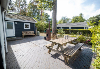Außenbereich des Nature Chalet im Bospark Markelo, Niederlande, mit Holzbänken und Gartenansicht.