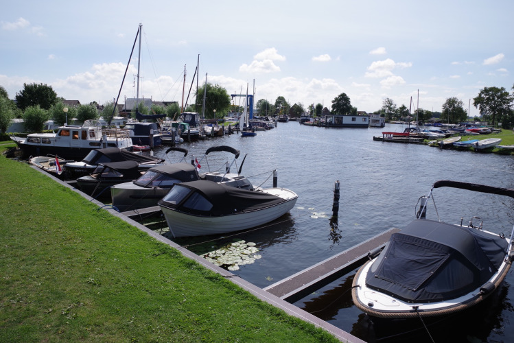 Foto vom Hafen mit Booten bei einem Ferienpark, Glamping-Unterkünften und grünen Flächen am Wasser.