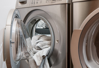 Open wasmachine met handdoeken in het gemeenschappelijke washok van een glamping vakantiepark.