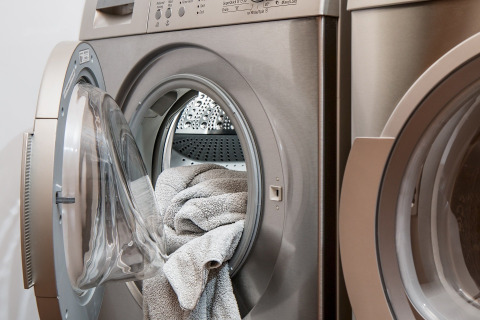 Open washing machine with towels inside found in the communal laundry room at a glamping holiday park.