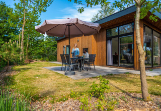 Koppel ontbijt op het terras van een glampingverblijf in een groene omgeving van een vakantiepark.