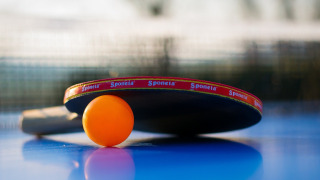 Raqueta de ping pong y bola naranja en mesa, foto tomada en un parque vacacional con glamping.