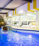 Piscina cubierta en un parque vacacional con familias disfrutando de un ambiente colorido y relajante.