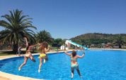 Drei Frauen springen in den Pool im Camping Mas Patoxas, Katalonien, Spanien, an einem sonnigen Tag.