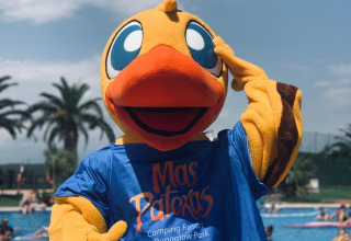 Maskot i andedragt fra Mas Patoxas Camping Resort står ved en swimmingpool fyldt med feriegæster.
