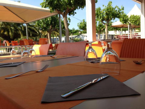 Area pranzo all’aperto con sedie arancioni al Camping Mas Patoxas, villaggio vacanze in Catalogna, Spagna.