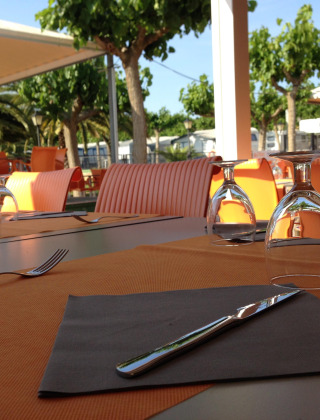 Zona de comedor al aire libre con sillas naranjas en Camping Mas Patoxas, un parque vacacional en Cataluña, España.