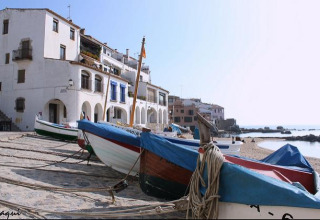 Fishing boats on the sandy shore in front of whitewashed buildings in the coastal town of Pals, Catalonia, Spain.