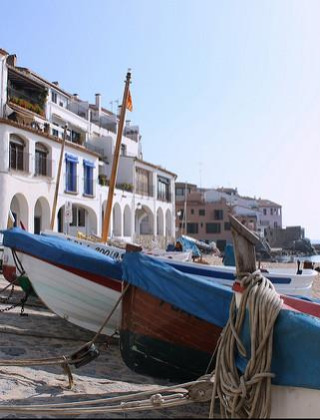 Barcas de pesca en la playa de arena frente a casas blancas en la localidad costera de Pals, Cataluña, España.
