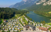 Camping Seeblick Toni holiday park in Tirol, Austria, set by a scenic lake, mountains, and camper vans.