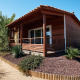 Træchalet Bungalow Quermany med en overdækket terrasse og ørkenhave under klar blå himmel.
