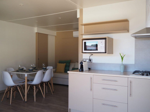 Cocina moderna y comedor en el Bungalow Quermany de Camping Mas Patoxas, España, con decoración luminosa.