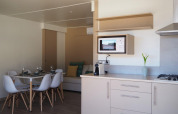 Cocina moderna y comedor en el Bungalow Quermany de Camping Mas Patoxas, España, con decoración luminosa.
