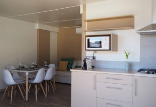 Cocina moderna y comedor en el Bungalow Quermany de Camping Mas Patoxas, España, con decoración luminosa.