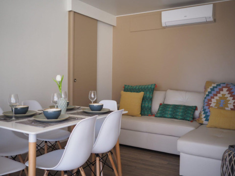Zona pranzo e soggiorno del Bungalow Quermany, Camping Mas Patoxas, Spagna, con arredo moderno.