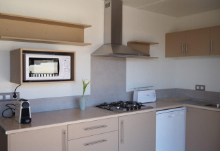 Cocina moderna en el Bungalow Quermany del Camping Mas Patoxas, España, con estufa, microondas y cafetera.