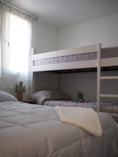 Camera al Bunaglow Quermany, Camping Mas Patoxas, con letto singolo, letto a castello e peluche.