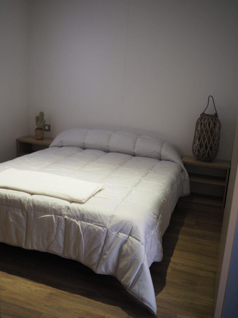 Slaapkamer in Bungalow Quermany bij Camping Mas Patoxas, Spanje, met tweepersoonsbed en eenvoudige inrichting.