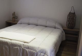 Chambre du Bungalow Quermany au Camping Mas Patoxas, Espagne, avec un lit double et une décoration épurée et chaleureuse.