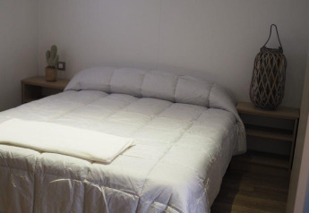 Chambre du Bungalow Quermany au Camping Mas Patoxas, Espagne, avec un lit double et une décoration épurée et chaleureuse.