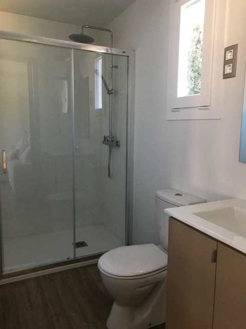 Bagno moderno con doccia, WC e lavandino in uno chalet del Bungalow Quermany, Camping Mas Patoxas, Spagna.