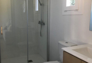 Moderne badkamer met douche, toilet en wastafel in een chalet van Bungalow Quermany, Camping Mas Patoxas, Spanje.